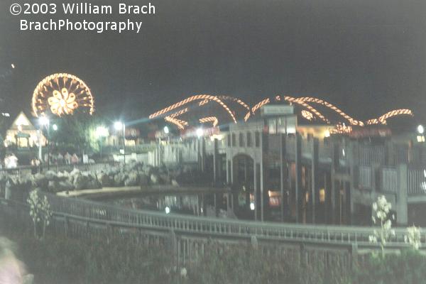 Tidal Force's soaking bridge at night with the Ferris Wheel and Lightning Racer in the background.