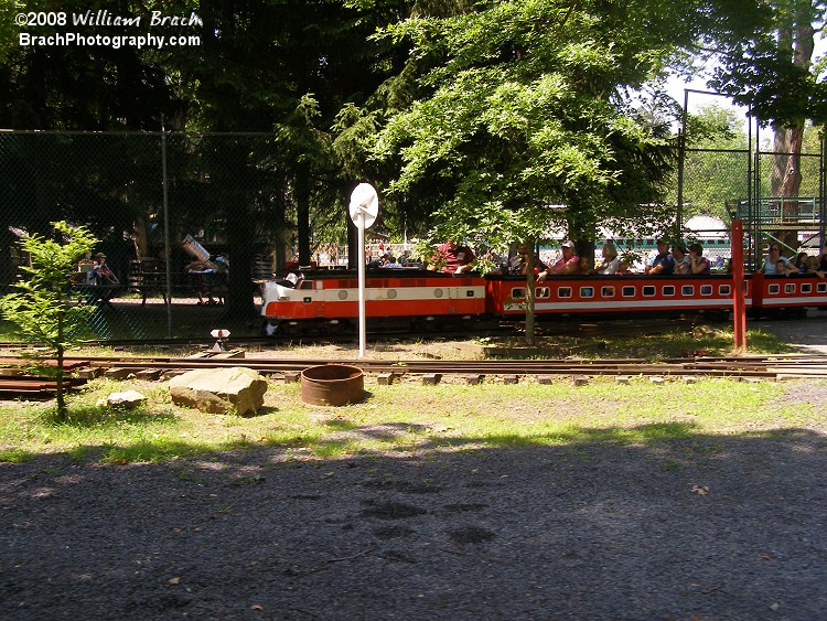 The red train departing the station area as the train I was on approaches the station.