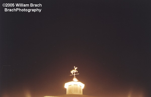 Wind direction indicator all lit up on the top of the Carousel Building at night.